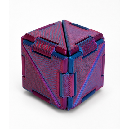 Cubo Cubigami transformable impreso en 3D en colores magenta y azul con diseño geométrico articulado.